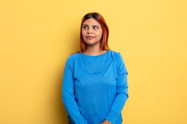 Genç İspanyol kadın merak ediyor, mutlu düşünceler ve fikirler düşünüyor, hayal kuruyor, kenarda yer arıyor.