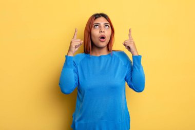 Genç İspanyol kadın şaşkınlık içinde ve ağzı açık. Şok olmuş ve şaşırmış bir bakışla yukarı bakıyor.