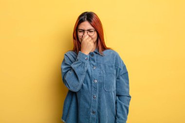 Genç İspanyol kadın iğreniyor, kötü ve nahoş bir koku duymamak için burnunu tutuyor.