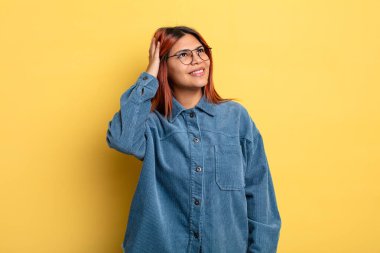 Genç İspanyol kadın neşeli ve sıradan bir şekilde gülümsüyor, olumlu, mutlu ve kendinden emin bir bakışla yumruk yumruğa.