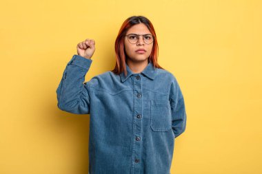 Genç İspanyol kadın ciddi, güçlü ve isyankar hissediyor, yumruğunu kaldırıyor, protesto ediyor ya da devrim için savaşıyor.