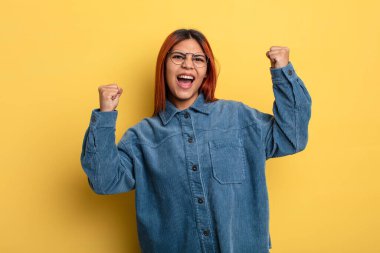 Genç İspanyol kadın öfkeli bir ifadeyle ya da yumruklarıyla saldırganca bağırıyor başarıyı kutluyor.