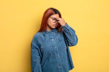 Genç İspanyol kadın stresli, mutsuz ve hayal kırıklığına uğramış, alınına dokunmuş ve şiddetli baş ağrısı çeken.