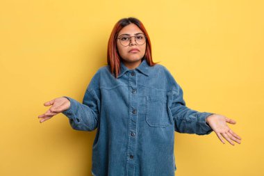 Genç İspanyol kadın şaşkın ve şaşkın hissediyor, doğru cevap veya karardan emin değil, bir seçim yapmaya çalışıyor.