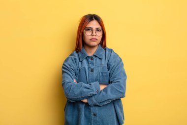 Genç İspanyol kadın hayal kırıklığına uğramış, hayal kırıklığına uğramış, ciddi görünüyor, kızgın ve kollarını kavuşturmuş.