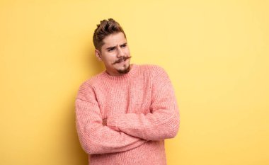 Genç yakışıklı bir adam şüphe ediyor ya da düşünüyor, dudağını ısırıyor ve kendine güveni yok ve gergin hissediyor, bir yandan da uzayı taklit etmeye çalışıyor. Garip bıyık konsepti