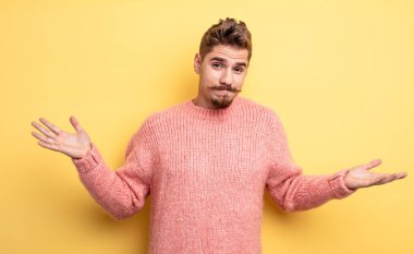 Genç yakışıklı adam şaşkın ve şaşkın, şüpheci, farklı seçenekleri tartıyor ya da komik bir ifadeyle seçiyor. Garip bıyık konsepti 