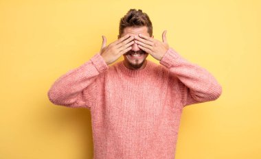 Genç yakışıklı adam gülümsüyor ve mutlu hissediyor, iki eliyle gözlerini kapatıyor ve inanılmaz bir sürpriz bekliyor. Garip bıyık konsepti