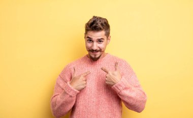 Genç yakışıklı adam mutlu, şaşırmış ve gururlu hissediyor, heyecanlı ve şaşkın bir bakışla kendini işaret ediyor. Garip bıyık konsepti