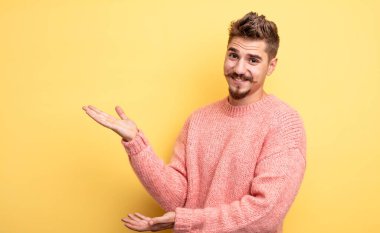 Genç yakışıklı adam gururla ve özgüvenle gülümsüyor, mutlu ve tatmin olmuş hissediyor ve fotokopi alanında bir konsept gösteriyor. Garip bıyık konsepti