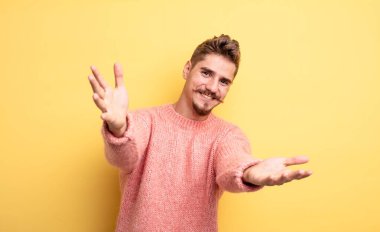 Genç yakışıklı adam neşeyle gülümsüyor sıcak, dostça, sevgi dolu bir kucak veriyor, mutlu ve sevimli hissediyor. Garip bıyık konsepti