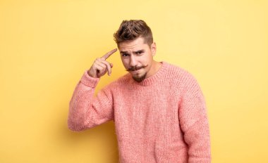 Genç yakışıklı adam kafası karışık ve şaşkın hissediyor. Deli, deli ya da aklını kaçırmış olduğunu gösteriyor. Garip bıyık konsepti