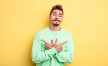 Kafası karışmış, güvensiz ve şüpheyle zıt yönlere bakan genç ve yakışıklı bir adam. Garip bıyık konsepti