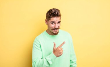 Genç ve yakışıklı bir adam heyecanlı ve şaşırmış görünüyor. Yana ve yukarı doğru uzayı işaret ediyor. Garip bıyık konsepti