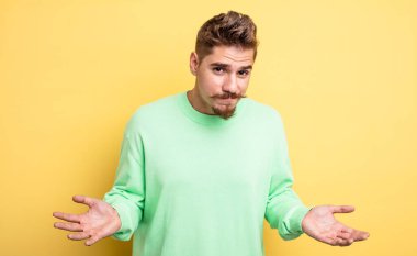 young handsome man feeling clueless and confused, having no idea, absolutely puzzled with a dumb or foolish look. strange moustache concept