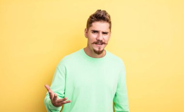 Genç ve yakışıklı bir adam sinirli, sinirli ve sinirli görünüyor. Senin neyin var? Garip bıyık konsepti 