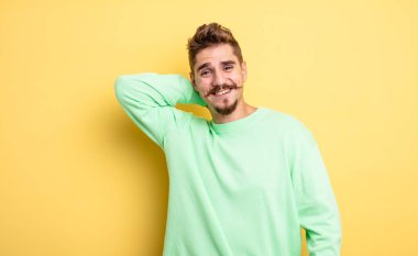 Genç ve yakışıklı bir adam neşeli ve kendinden emin bir şekilde gülüyor. Sıradan, mutlu, dostane bir gülümsemeyle. Garip bıyık konsepti