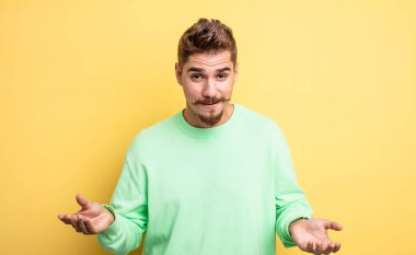 Genç yakışıklı bir adam bilgisiz ve kafası karışık, hangi seçeneği seçeceğinden emin değil, merak ediyor. Garip bıyık konsepti