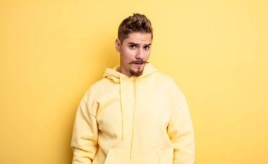 young handsome man feeling puzzled and confused, with a dumb, stunned expression looking at something unexpected. strange moustache concept