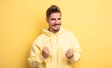 Genç yakışıklı adam zaferle bağırıyor, gülüyor ve mutlu hissediyor ve başarıyı kutlarken heyecanlanıyor. Garip bıyık konsepti