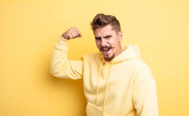 Genç yakışıklı adam kendini mutlu, tatmin olmuş ve güçlü hissediyor, kaslı ve formda, spor salonundan sonra güçlü görünüyor. Garip bıyık konsepti