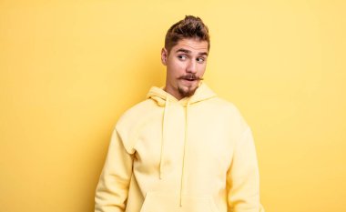 Genç yakışıklı adam şok olmuş, mutlu, şaşkın ve şaşırmış hissediyor, ağzı açık bir şekilde yana bakıyor. Garip bıyık konsepti