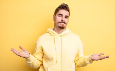 Genç yakışıklı adam şaşkın ve şaşkın hissediyor, doğru cevap ya da karardan emin değil, bir seçim yapmaya çalışıyor. Garip bıyık konsepti