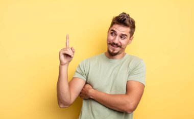 Genç yakışıklı adam mutlu bir şekilde gülümsüyor ve yan bakıyor, merak ediyor, düşünüyor ya da bir fikri var. Garip bıyık konsepti