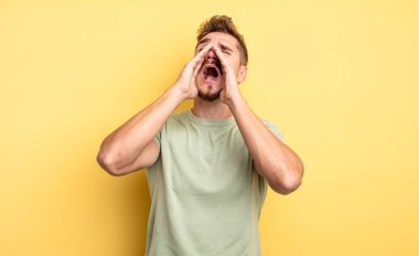 Genç yakışıklı adam mutlu, heyecanlı ve pozitif hissediyor. Elleri ağızda, bağırarak bağırıyor. Garip bıyık konsepti