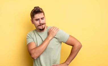 Genç yakışıklı adam yorgun, stresli, endişeli, hayal kırıklığına uğramış ve depresyonda, sırtı ya da boynu ağrıyan. Garip bıyık konsepti