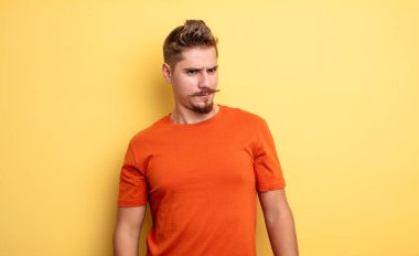 Genç, yakışıklı bir adam üzgün, üzgün ya da kızgın ve olumsuz bir tavır takınıyor, anlaşmazlık içinde kaşlarını çatıyor. Garip bıyık konsepti