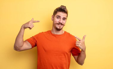 Genç yakışıklı adam, kendine güvenerek gülümsüyor. Geniş bir gülümseme, pozitif, rahat, tatmin olmuş bir tavır. Garip bıyık konsepti