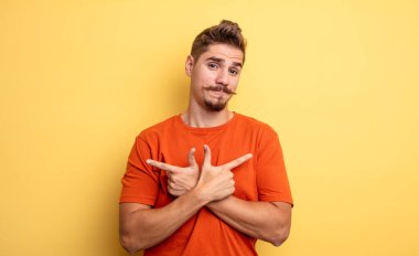 Kafası karışmış, güvensiz ve şüpheyle zıt yönlere bakan genç ve yakışıklı bir adam. Garip bıyık konsepti