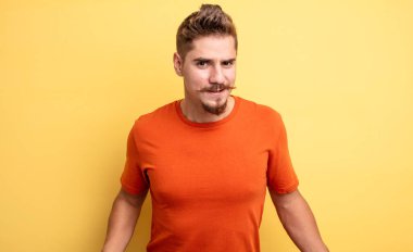 young handsome man feeling clueless and confused, having no idea, absolutely puzzled with a dumb or foolish look. strange moustache concept