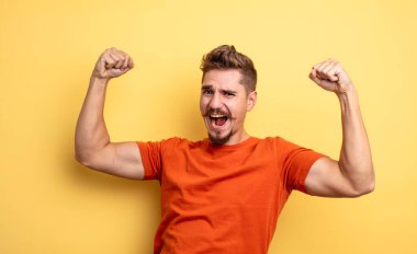 Genç yakışıklı adam zaferle bağırıyor, heyecanlı, mutlu ve şaşırmış görünüyor, kutlama yapıyor. Garip bıyık konsepti