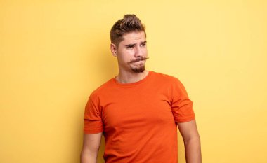 Kafası karışmış, kafası karışmış, bir sorunu çözmeye çalışan ya da çözmeye çalışan genç yakışıklı bir adam. Garip bıyık konsepti