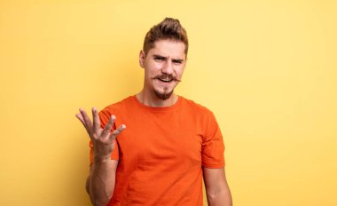 Genç ve yakışıklı bir adam sinirli, sinirli ve sinirli görünüyor. Senin neyin var? Garip bıyık konsepti 