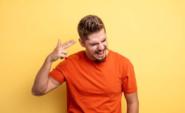 Genç yakışıklı adam mutsuz ve stresli görünüyor, intihar jesti elle silah işareti yapıyor, kafasını işaret ediyor. Garip bıyık konsepti