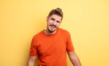 Kafası karışmış ve kafası karışmış genç yakışıklı bir adam gergin bir hareketle dudağını ısırıyor, sorunun cevabını bilmiyor. Garip bıyık konsepti