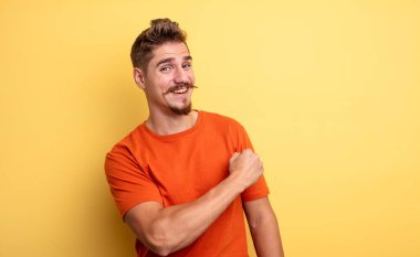 Genç yakışıklı bir adam mutlu, pozitif ve başarılı hissediyor, bir meydan okumayla karşılaştığında ya da iyi sonuçları kutladığında motive oluyor. Garip bıyık konsepti