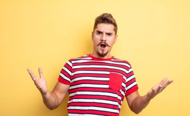 Genç ve yakışıklı bir adam son derece şok olmuş ve şaşırmış, endişeli ve paniklemiş, stresli ve dehşete kapılmış görünüyor. Garip bıyık konsepti