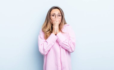 pretty caucasian woman feeling worried, upset and scared, covering mouth with hands, looking anxious and having messed up