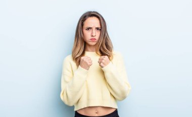 pretty caucasian woman looking confident, angry, strong and aggressive, with fists ready to fight in boxing position