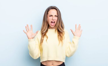 pretty caucasian woman screaming in panic or anger, shocked, terrified or furious, with hands next to head