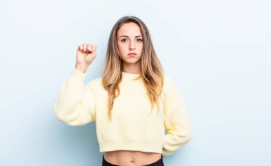 pretty caucasian woman feeling serious, strong and rebellious, raising fist up, protesting or fighting for revolution