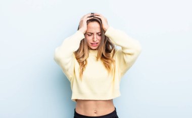 pretty caucasian woman feeling stressed and frustrated, raising hands to head, feeling tired, unhappy and with migraine