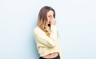 pretty caucasian woman feeling stressed, unhappy and frustrated, touching forehead and suffering migraine of severe headache