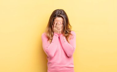 pretty caucasian woman feeling sad, frustrated, nervous and depressed, covering face with both hands, crying