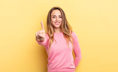 pretty caucasian woman smiling proudly and confidently making number one pose triumphantly, feeling like a leader