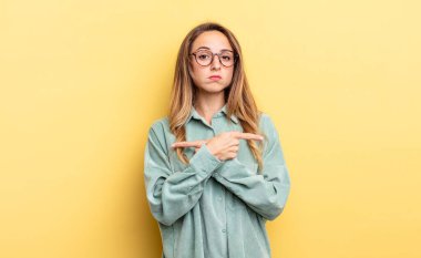 pretty caucasian woman looking puzzled and confused, insecure and pointing in opposite directions with doubts